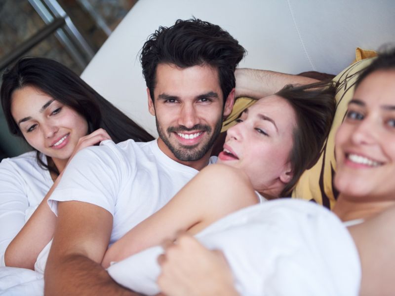 Homme avec trois femmes dans un lit